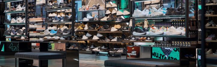Display of various sneaker models arranged on shelves in a retail environment, showcasing a range of styles and colors.