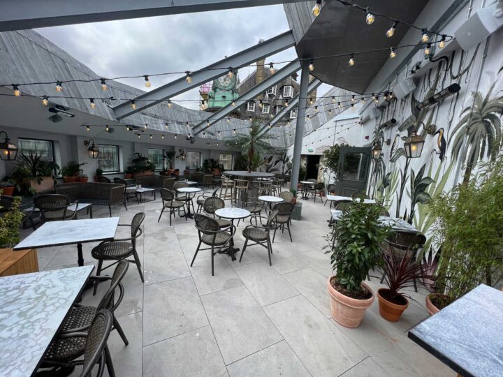 Charming outdoor cafe with empty tables and lush greenery